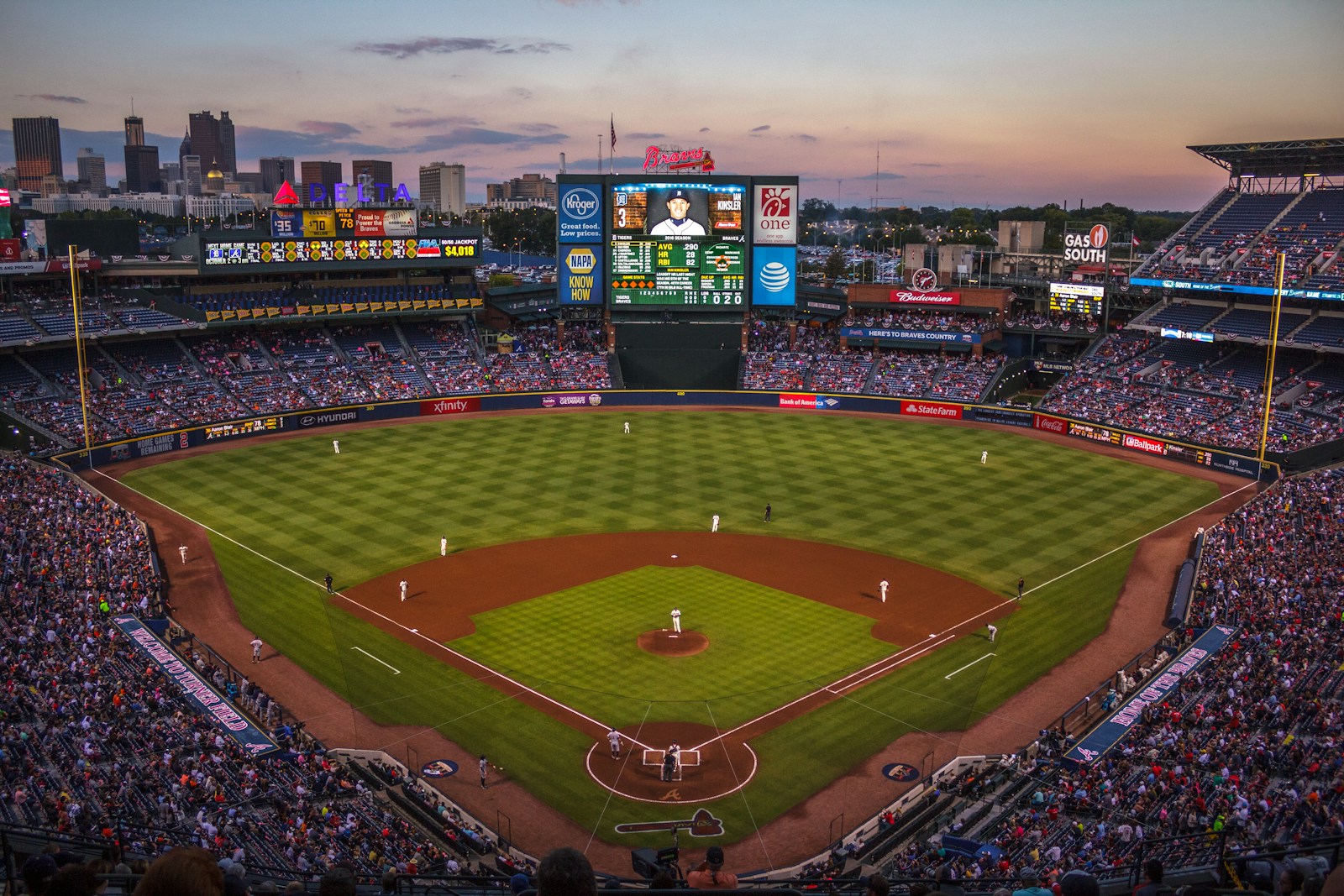 A baseball game at a ballpark at dusk.